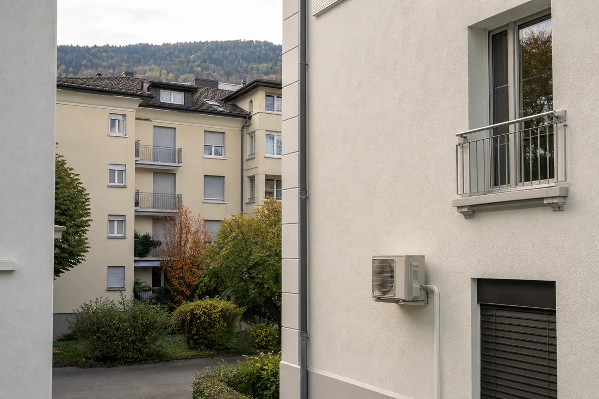 Unité extérieure de pompe à chaleur air-air sur un immeuble résidentiel de Bienne, avec les collines du Jura en arrière-plan